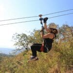 Photo by Ty Downs a woman is zipping through the air on a zip line