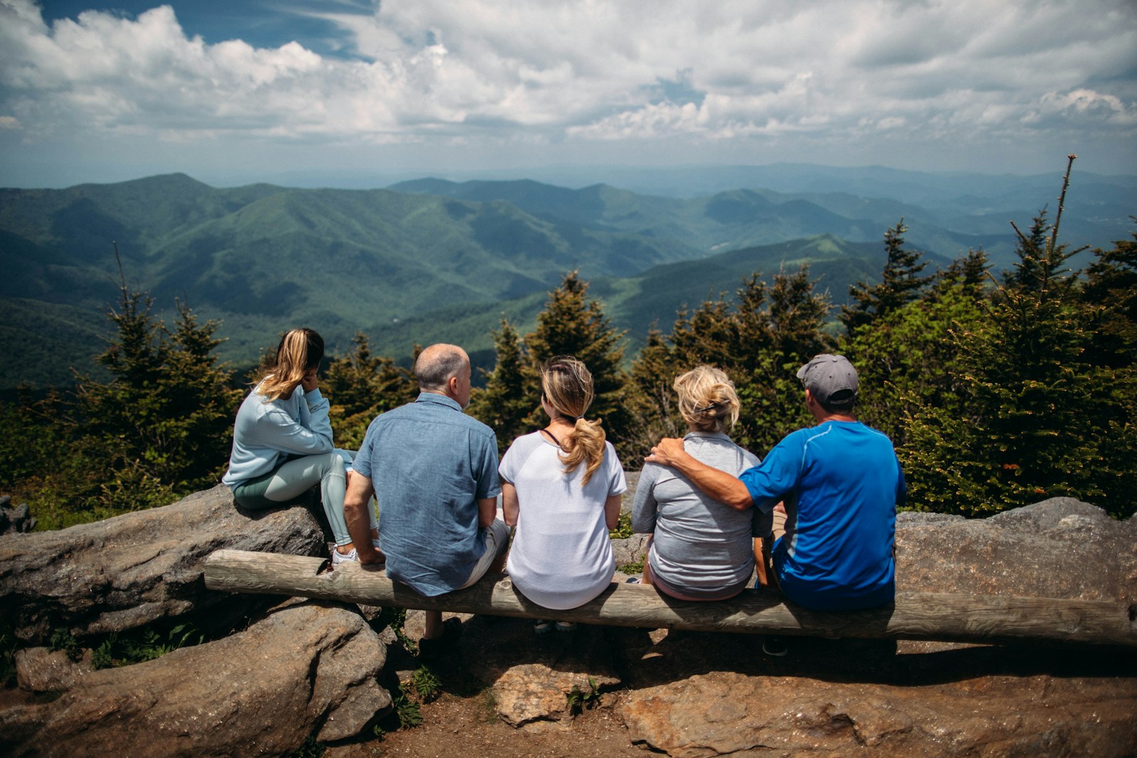 Photo by Roberto Nickson group of people sitting on rocks overlooking mountain