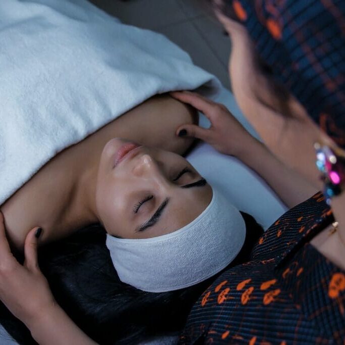 Photo by Masum Rahimi a woman laying in bed with a towel on her head